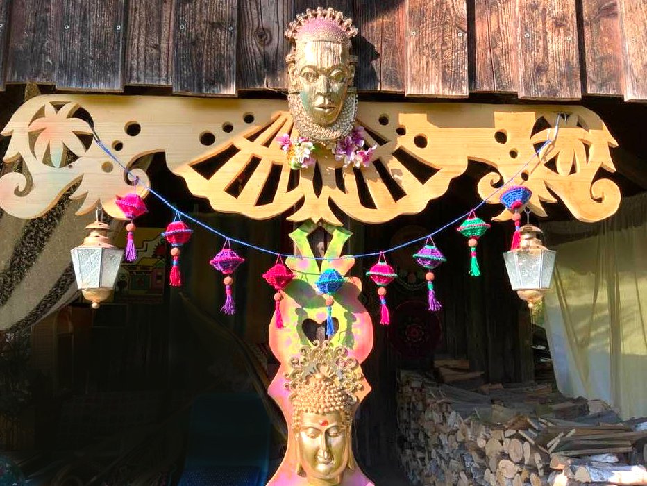 Reihe kleiner gehäkelter Lampions mit Quasten und Perlen an blauer Schnur vor Holzverzierung