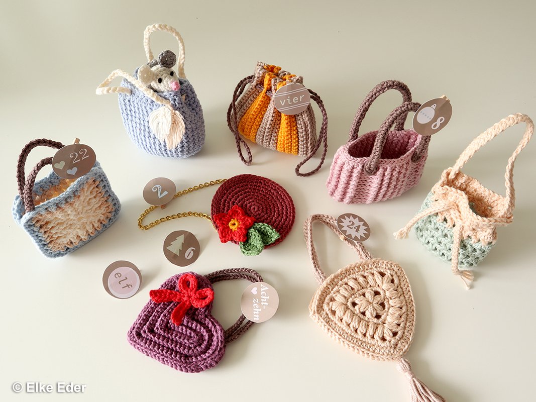 Many small, colorful crocheted bags and pouches arranged on a pale surface.