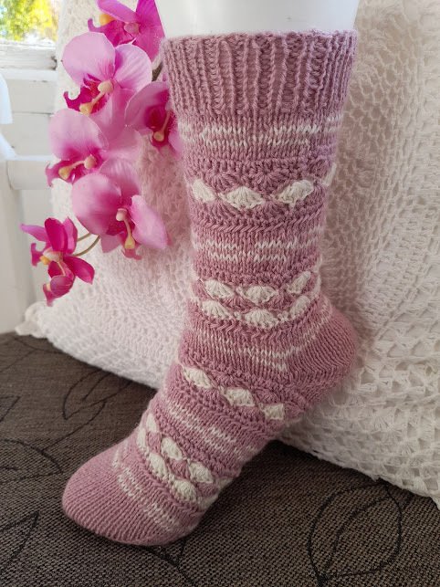 Rosa gestrickte Socke mit cremefarbenem Strukturmuster und Rippenbund