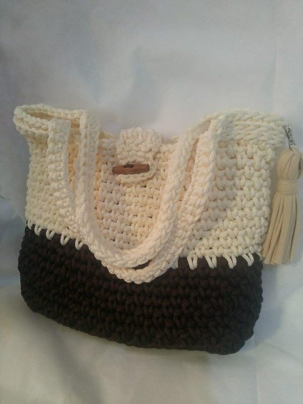 Two-tone crocheted shoulder bag in cream and dark brown with wooden toggle and tassel.