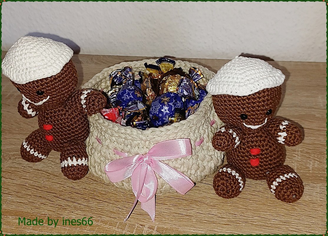 Gehäkelte Lebkuchenmännchen mit Zierkörbchen voller Pralinen und rosa Schleife