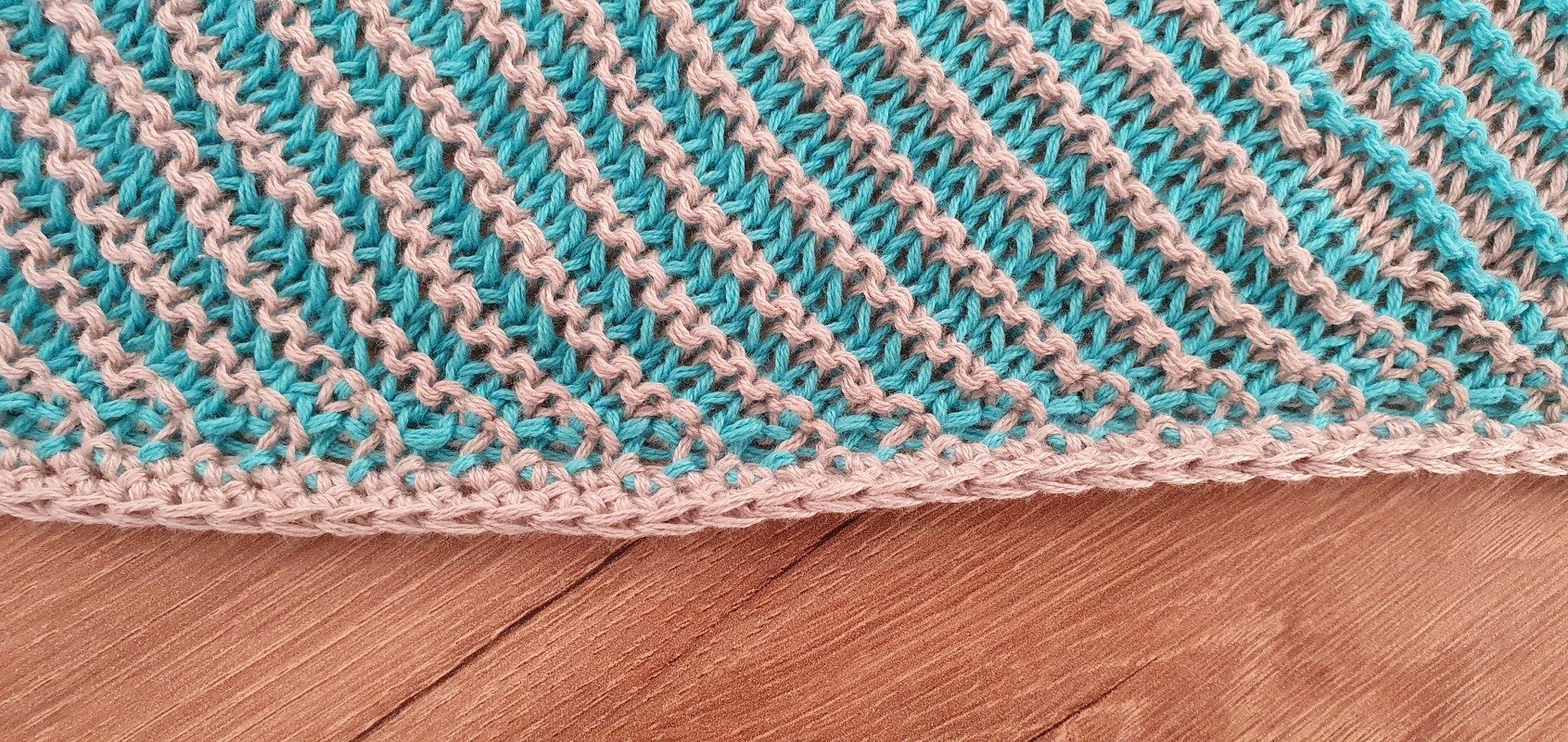 Close-up of teal and beige knit showing diagonal stitch repeat