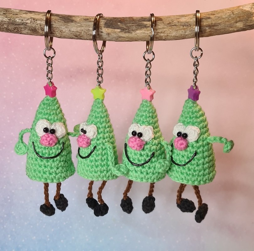 Vier gehäkelte grüne Weihnachtsbaum‑Schlüsselanhänger mit rosa Nase, weißen Perlenaugen und Metallringen