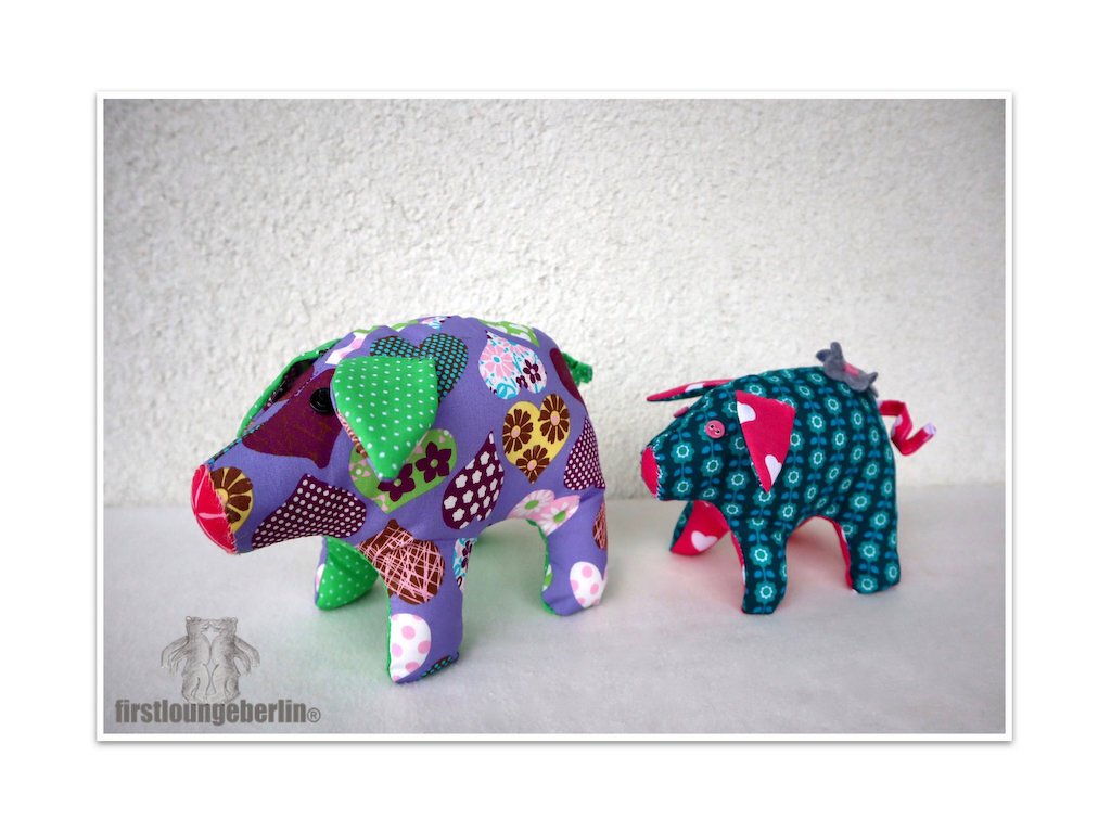 Zwei genähte Stoffschweinchen aus gemustertem Stoff in Violett und Türkis