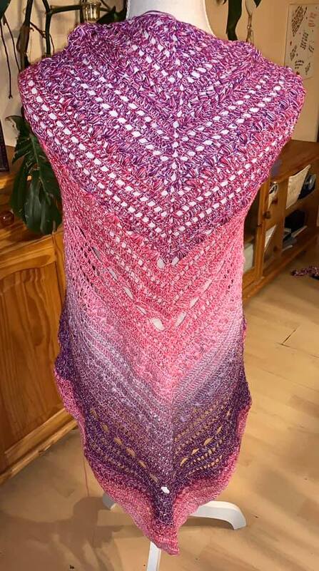 Gehäkeltes Dreieckstuch in Rosa- und Purpurtönen mit offenem Lückenmuster auf Schneiderpuppe