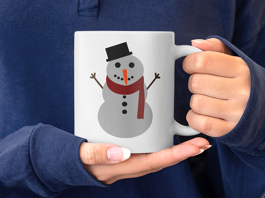 Hände halten eine weiße Tasse mit Schneemann-Motiv, Zylinder, rotem Schal und Karottennase