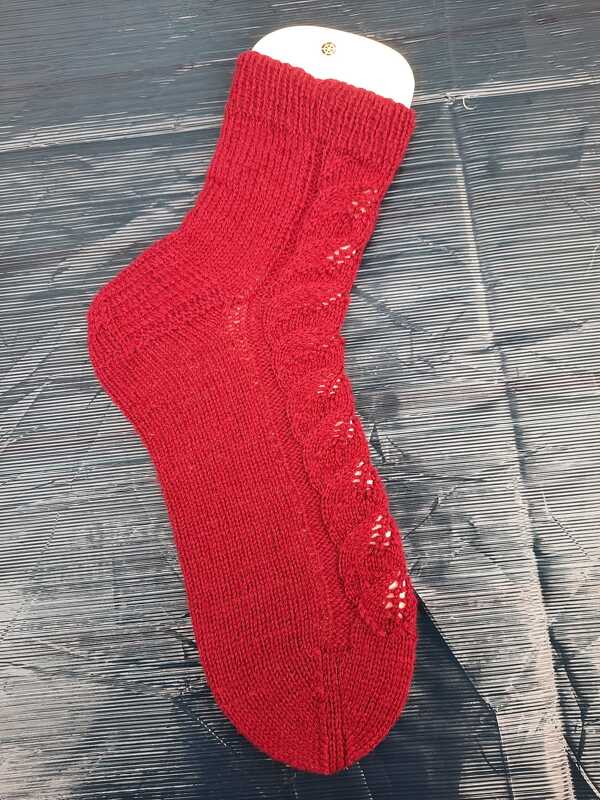 Rote gestrickte Damensocke mit Lochmuster auf dunklem Untergrund