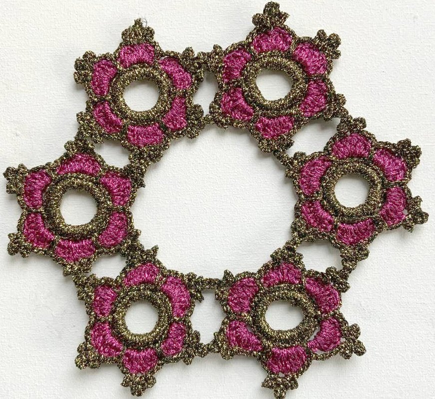 Magenta-goldenes gehäkeltes Deckchen in sternförmigem Ring auf hellem Untergrund