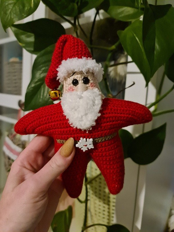 Gehäkelter sternförmiger Weihnachtsmann-Amigurumi in Rot mit weißem Bart und goldener Glocke
