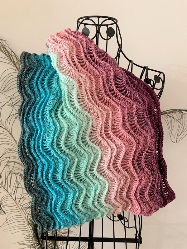 Rippling ombre crocheted scarf in teal, mint, pink and plum draped on a black wire dress form.
