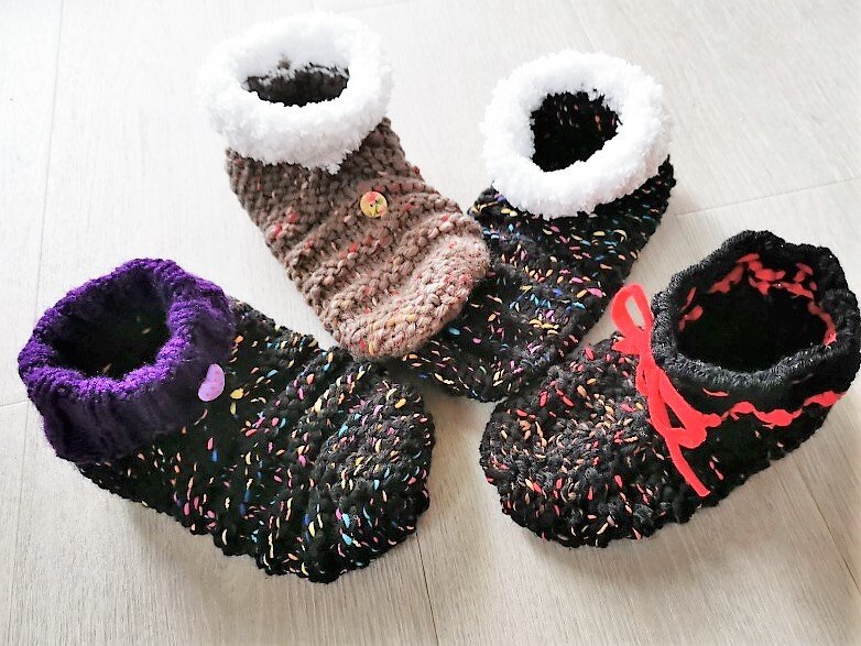 Vier Paar gestrickte Hausschuhe für Damen, zwei mit weißem Plüschrand und zwei mit farbigen Bündchen sowie bunten Sprenkeln