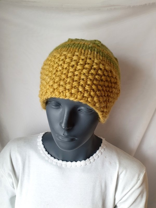 Grobgestrickte senfgelbe Mütze mit olivgrünem Verlauf auf einer Schaufensterpuppe