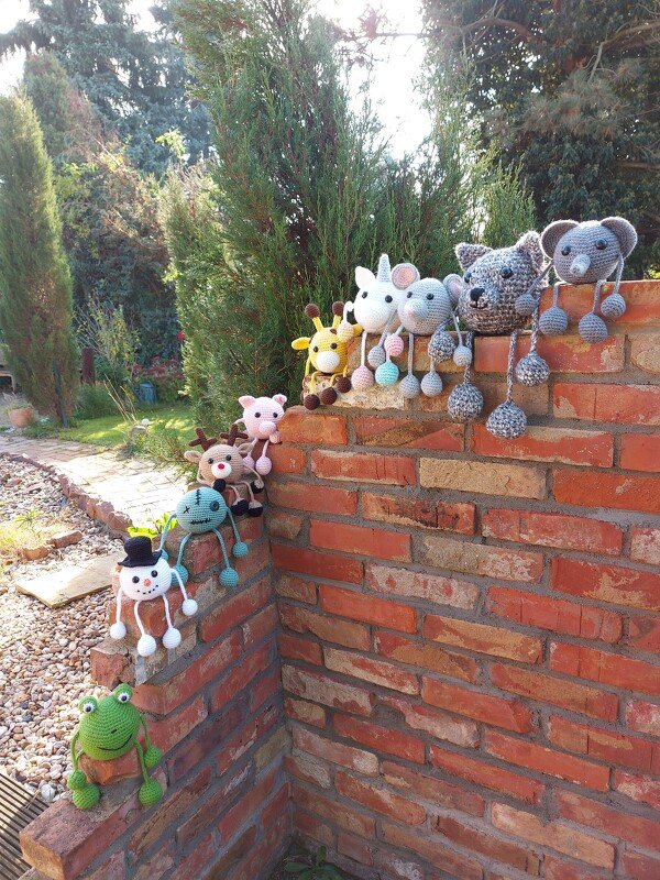 Verschiedene gehäkelte Amigurumi-Muster an einer Ziegelmauer zum Vergleich von Formen und Farben