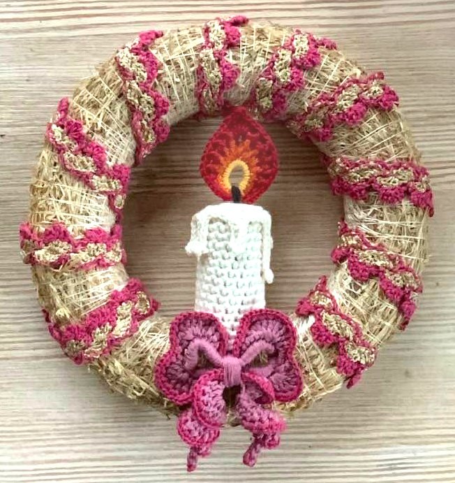 Strohring mit rosa-goldener gehäkelter Zickzack-Borte, weißer gehäkelter Kerze mit Flamme und rosa Häkel-Schleife