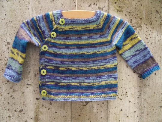 Gestrickte mehrfarbige Babyjacke mit seitlicher Knopfleiste und grünen Knöpfen