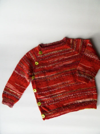 Rote gestrickte Babyjacke mit bunten Streifen und grünen Knöpfen, flach liegend