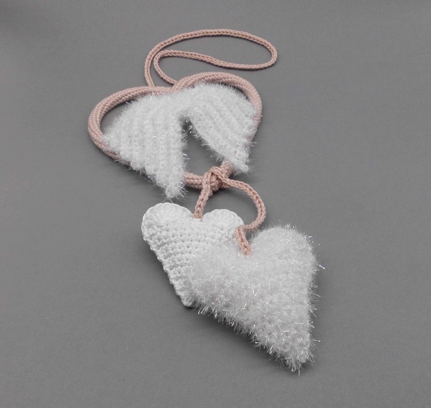 Gehäkeltes Herzpaar in Weiß mit flauschigem Garn, rosa Kordel und gehäkelten Flügeln