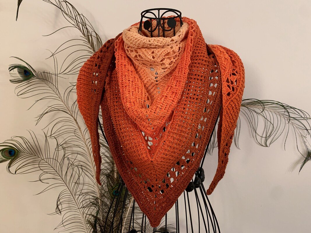 Wire dress form wearing a triangular crochet shawl in an orange gradient with alternating lace and solid stitch panels