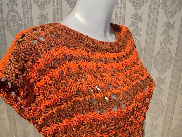 Gestrickter Kurzarm-Pullover in Orange- und Brauntönen mit Ajourmuster auf Schaufensterpuppe
