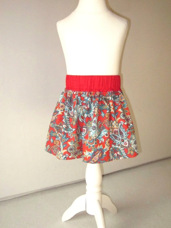 Kinderröckchen mit rotem Bund und buntem Paisley-Muster an weißer Schaufensterpuppe