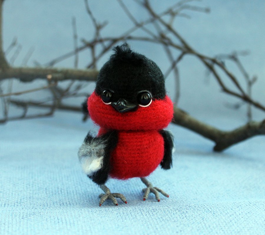 Amigurumi-Vogel mit rotem Körper und schwarzem Kopf in stehender Pose