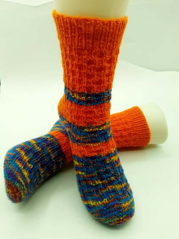 Gestrickte orange-bunte Socken auf hellem Untergrund