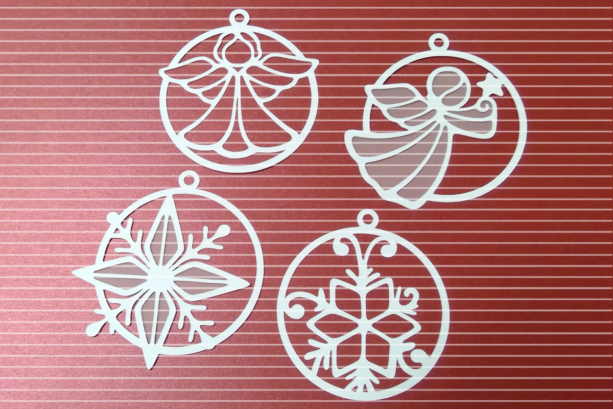 Vier weiße, filigrane Weihnachtsanhänger mit Engeln und Schneeflocken auf rotem Hintergrund