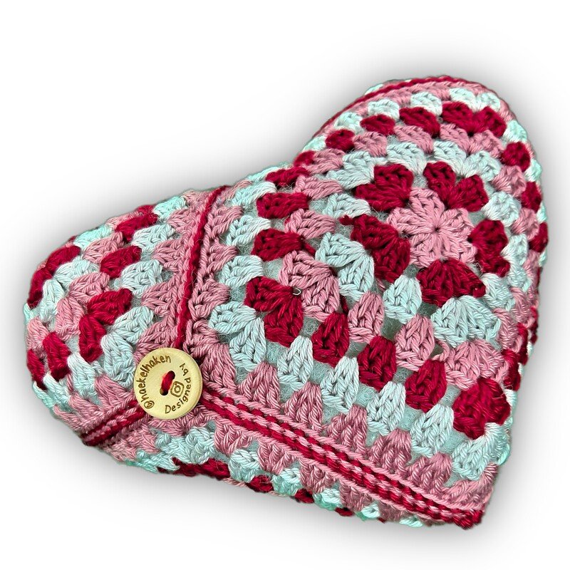 Gehäkeltes Herzkissen aus Granny-Squares in Rosa, Rot und Hellblau mit Holzknopf