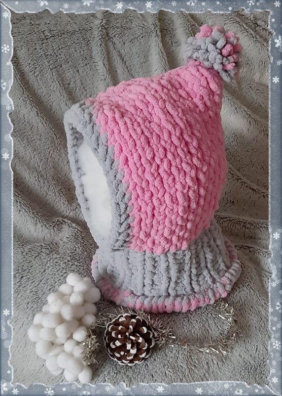 Gestrickte zweifarbige Kinder‑Schlupfmütze in Rosa und Grau mit Bommel auf grauem Plüschhintergrund