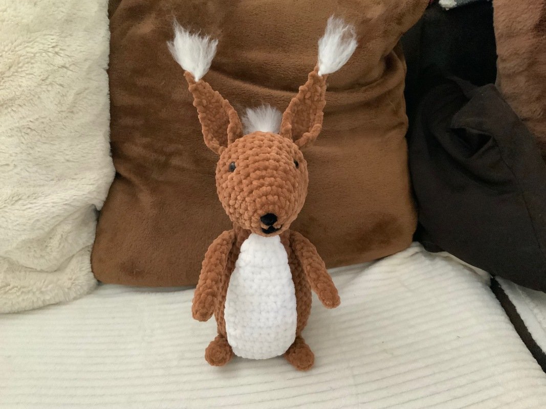 Gehäkeltes braunes Amigurumi-Tier mit weißem Bauch und Puschelohren, frontal
