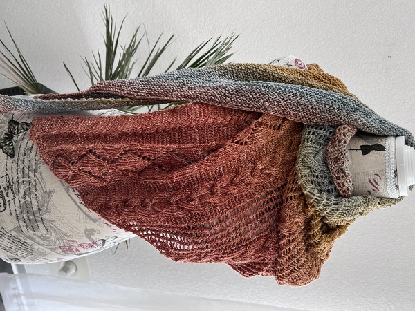 Gestricktes Dreieckstuch mit Farbverlauf (Terrakotta–Blaugrau–Gold), Zopf- und Ajourmuster, drapiert