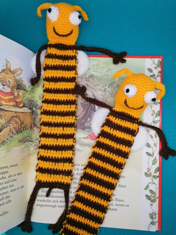 Zwei fröhliche gehäkelte Bienen-Lesezeichen auf einem aufgeschlagenen Kinderbuch