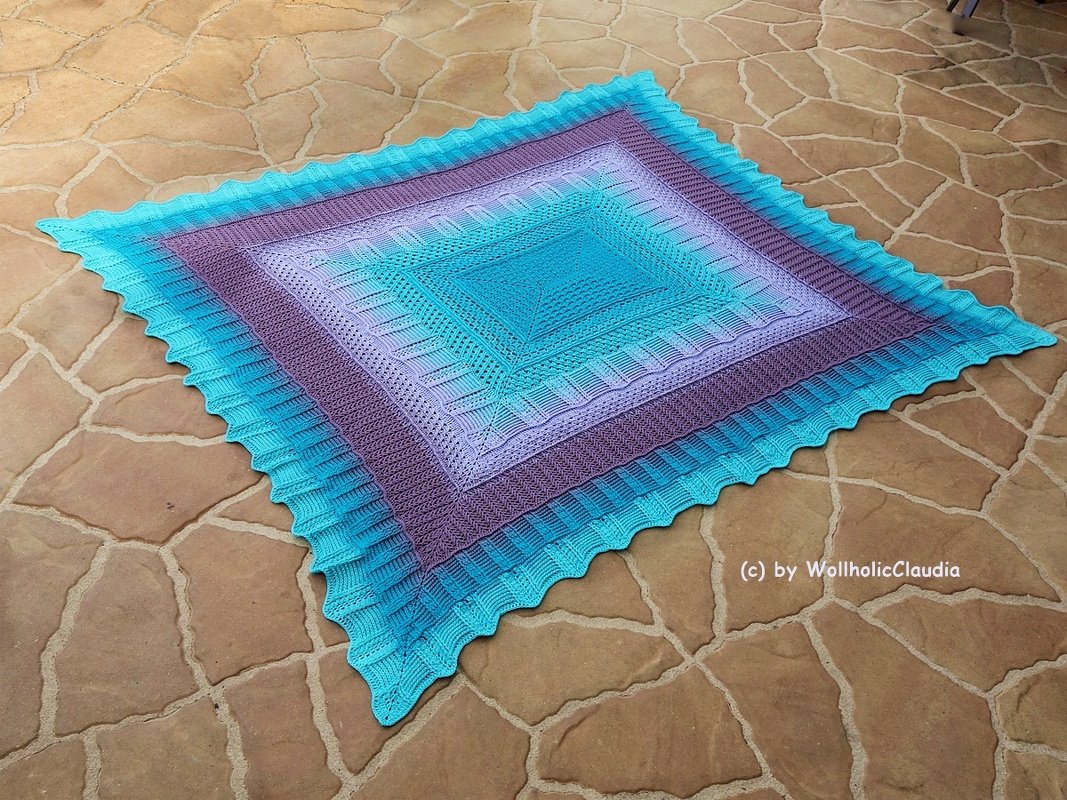 Quadratische gehäkelte Decke mit Farbverlauf von Türkis zu Lila auf Steinboden, mit gewelltem Rand
