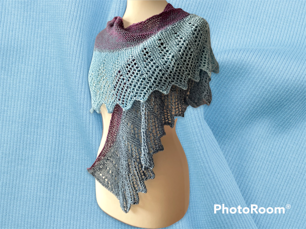 Gestricktes halbrundes Tuch in Bordeaux, Hellblau und Blaugrau mit Lochmuster, auf einer Schaufensterpuppe drapiert.