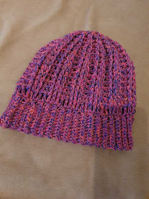 Gehäkelte Beanie in Pink und Lila mit Rippenbund auf hellem Hintergrund