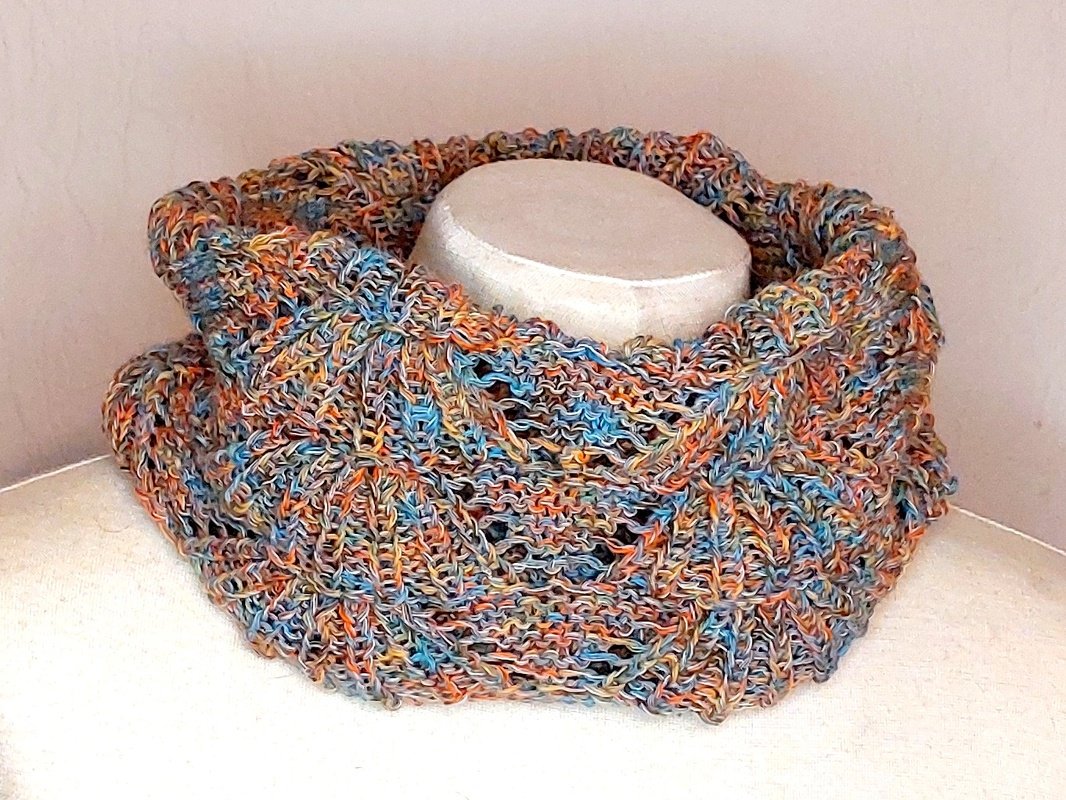 Bunter gestrickter Loopschal aus mehrfarbiger Wolle mit offenem Lochmuster auf cremefarbenem Dekomannequin.