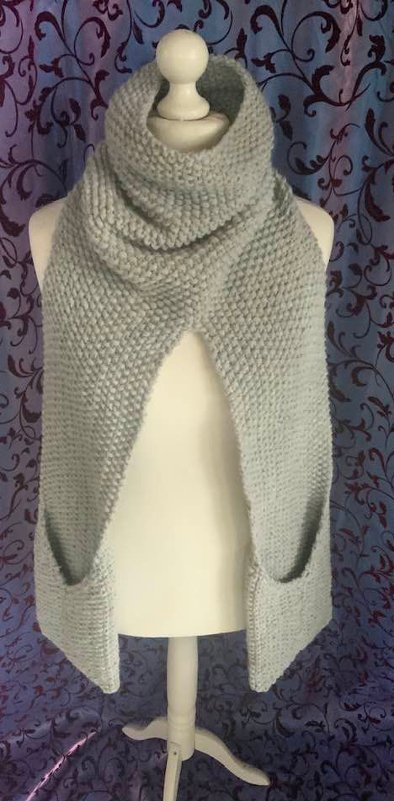 Hellgrauer, kraus-rechts gestrickter Schal mit weitem Rollkragen und Eingrifftaschen auf einer Schaufensterpuppe