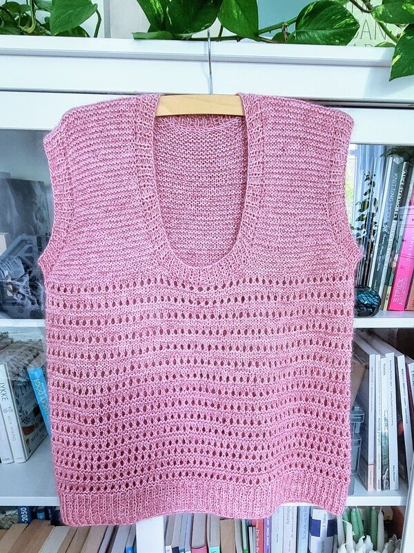 Rosafarbener gestrickter Damen-Pullunder mit U-Ausschnitt und Lochmuster, an Holzbügel aufgehängt