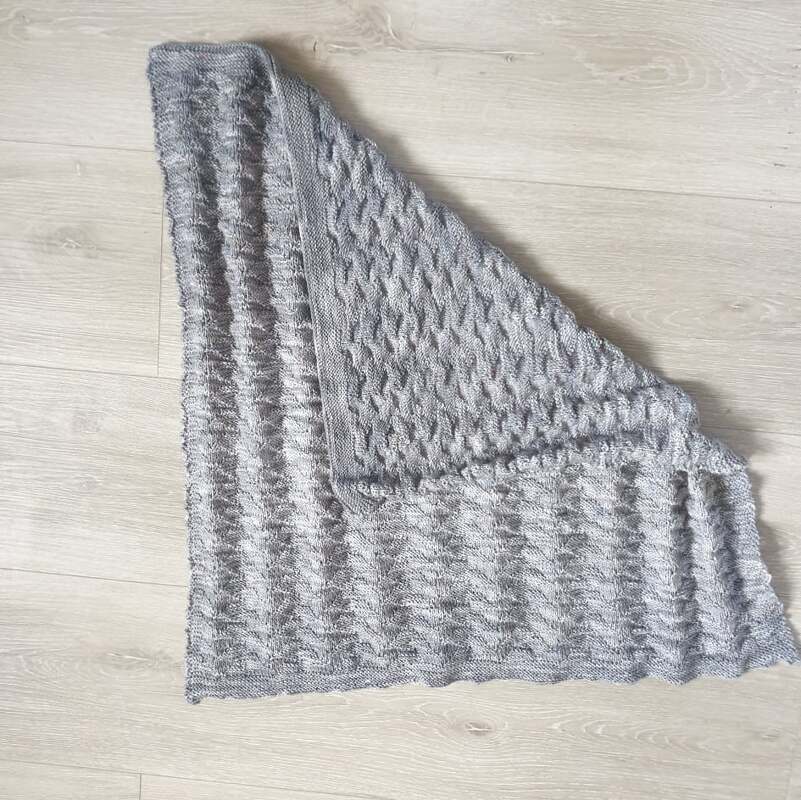 Gestrickte hellgraue Babydecke mit Rippenrand und strukturierter Fläche, Ecke umgeschlagen