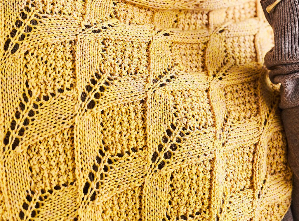 Detail der Maschenstruktur eines senfgelben Rechtecktuchs mit Lochreihen und reliefartigen Quadraten