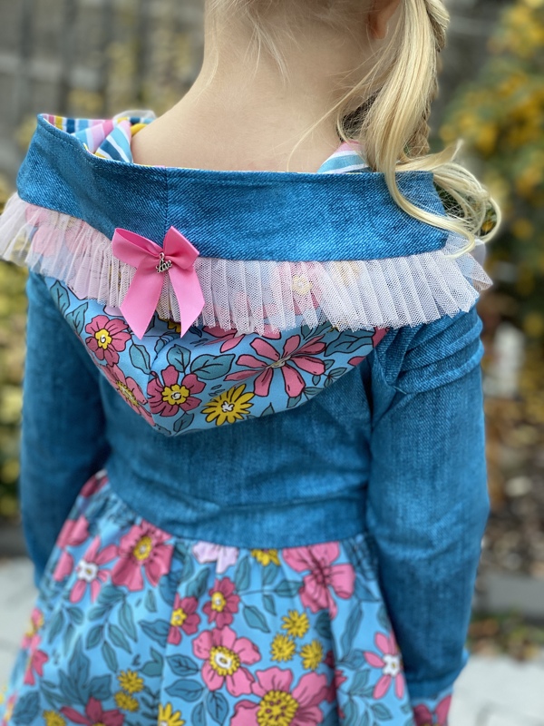 Rückenansicht eines Kapuzenkleids mit gerafftem Rock, floraler Kapuzeninnenseite und Tüllbesatz