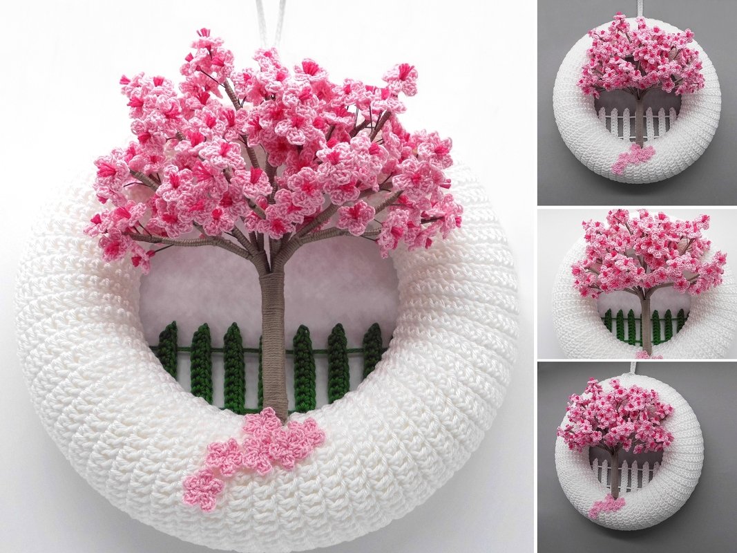 White crocheted wreath with a pink cherry blossom tree and miniature picket fence.