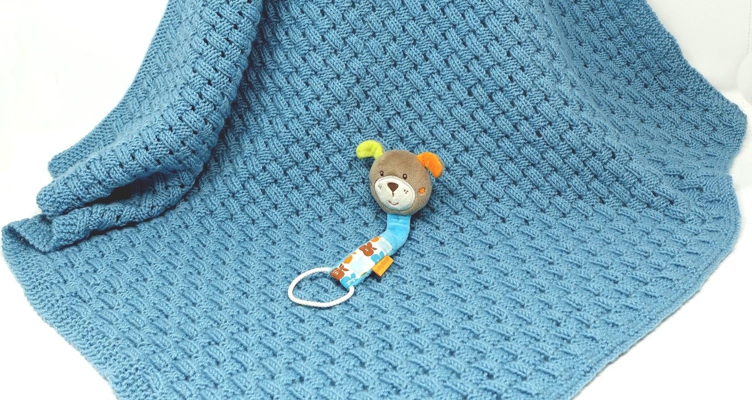 Blaue gestrickte Babydecke mit Flechtmuster und kleinem Stofftier