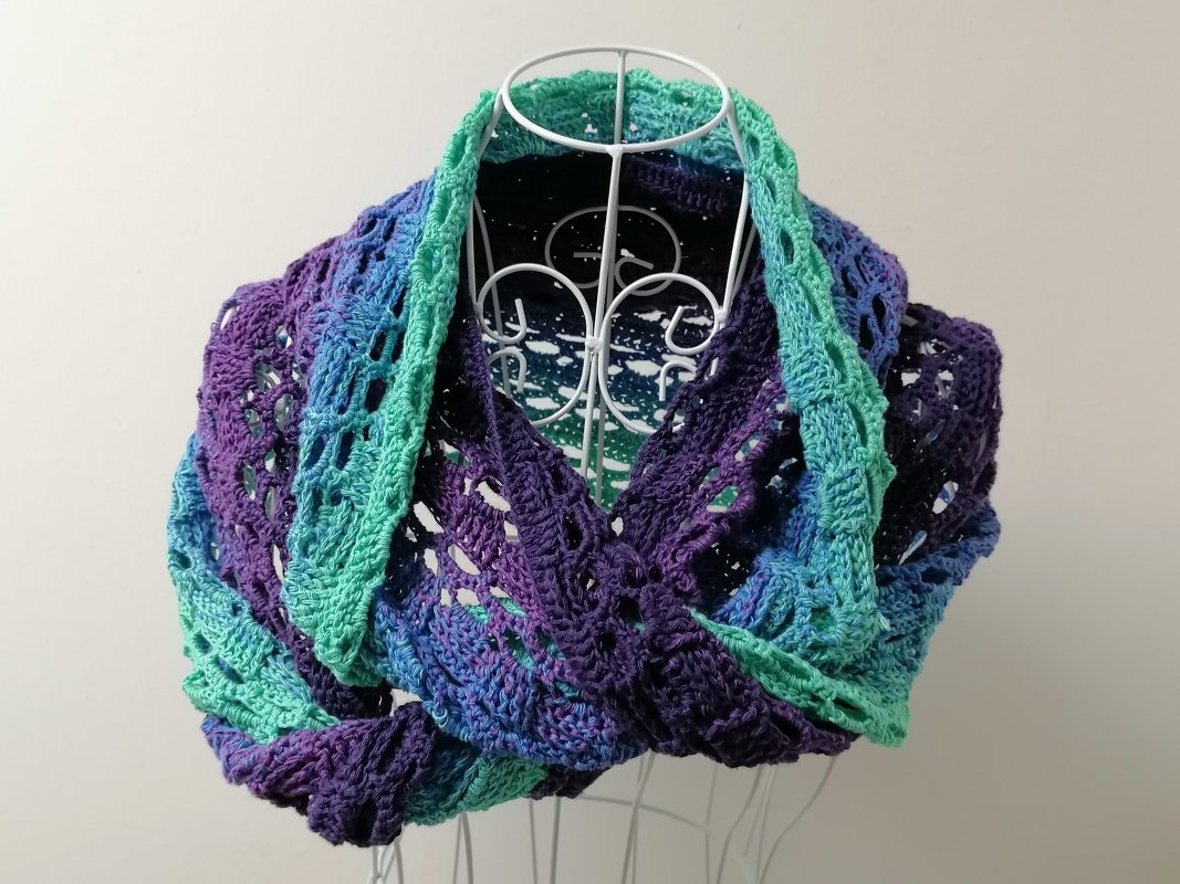 Lacy crochet infinity scarf cowl in teal, blue and purple on a white wire dress form