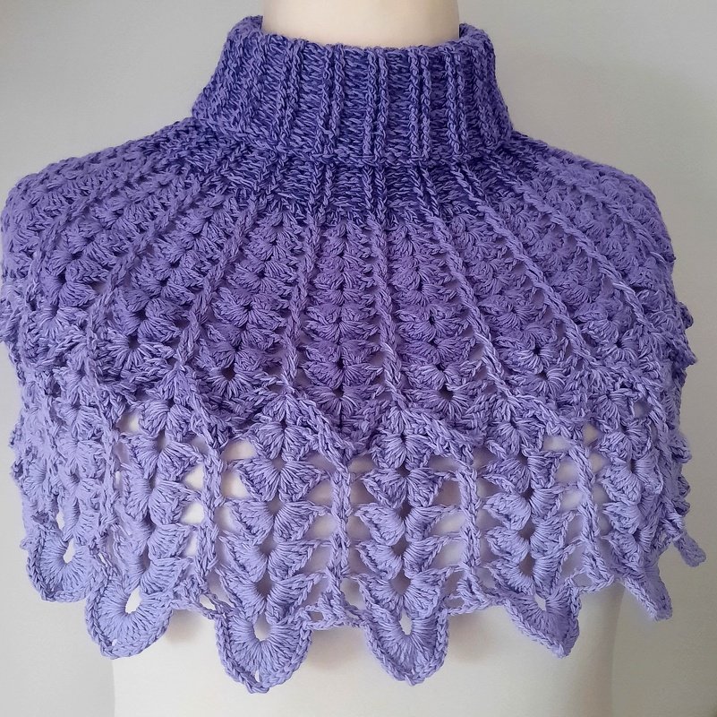 Lila gehäkelter Kragenschal mit hohem Rollkragen und Muschelmuster auf einer Schaufenpuppe.