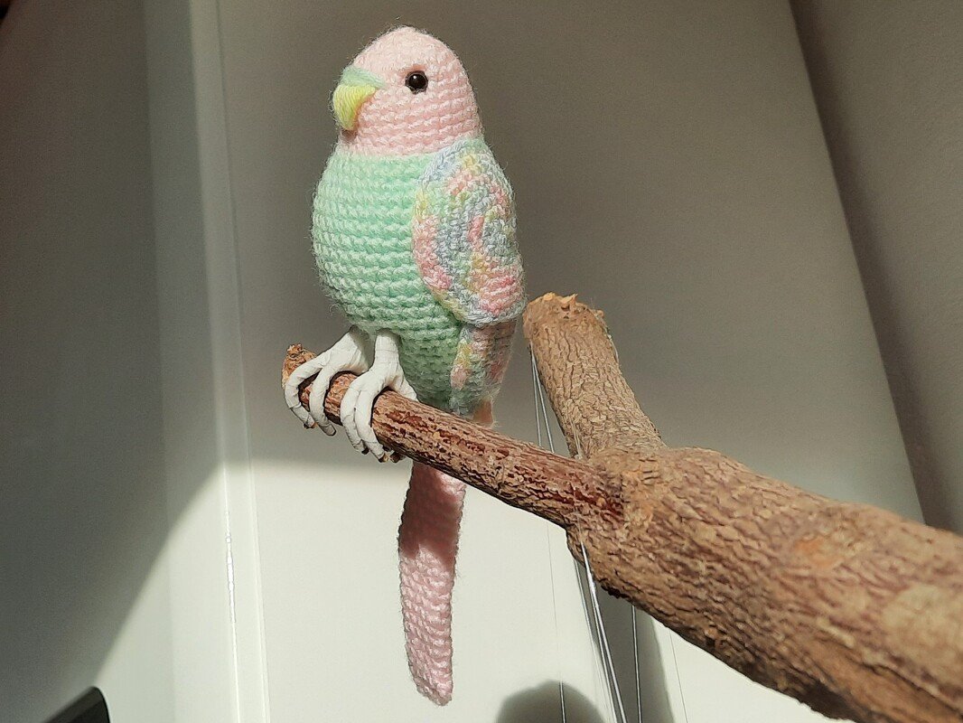 Nahaufnahme gehäkelter Amigurumi-Vogel mit Flügelmuster und Krallen