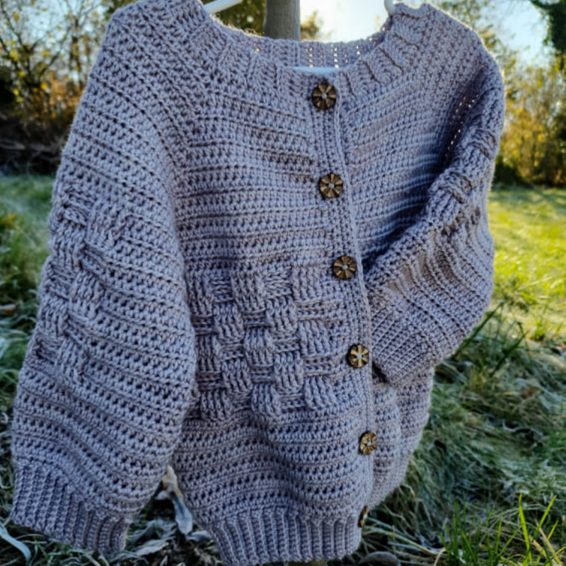 Gehäkelte hellgraue Babyjacke mit Holzknöpfen an Kleiderbügel