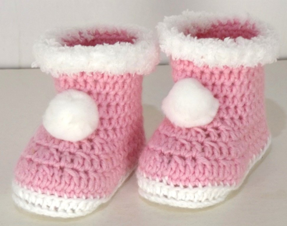 Rosa gehäkelte Babyschuhe mit weißem Bommel und flauschigem Bund.