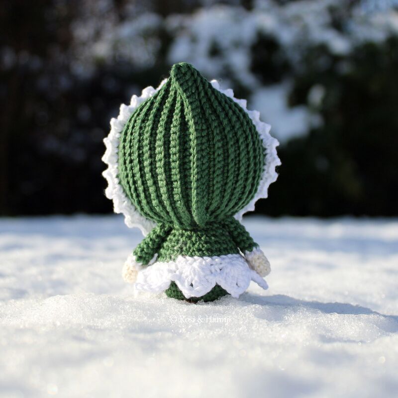 Gehäkelte Amigurumi-Winterpuppe in Grün und Weiß, Rückansicht im Schnee