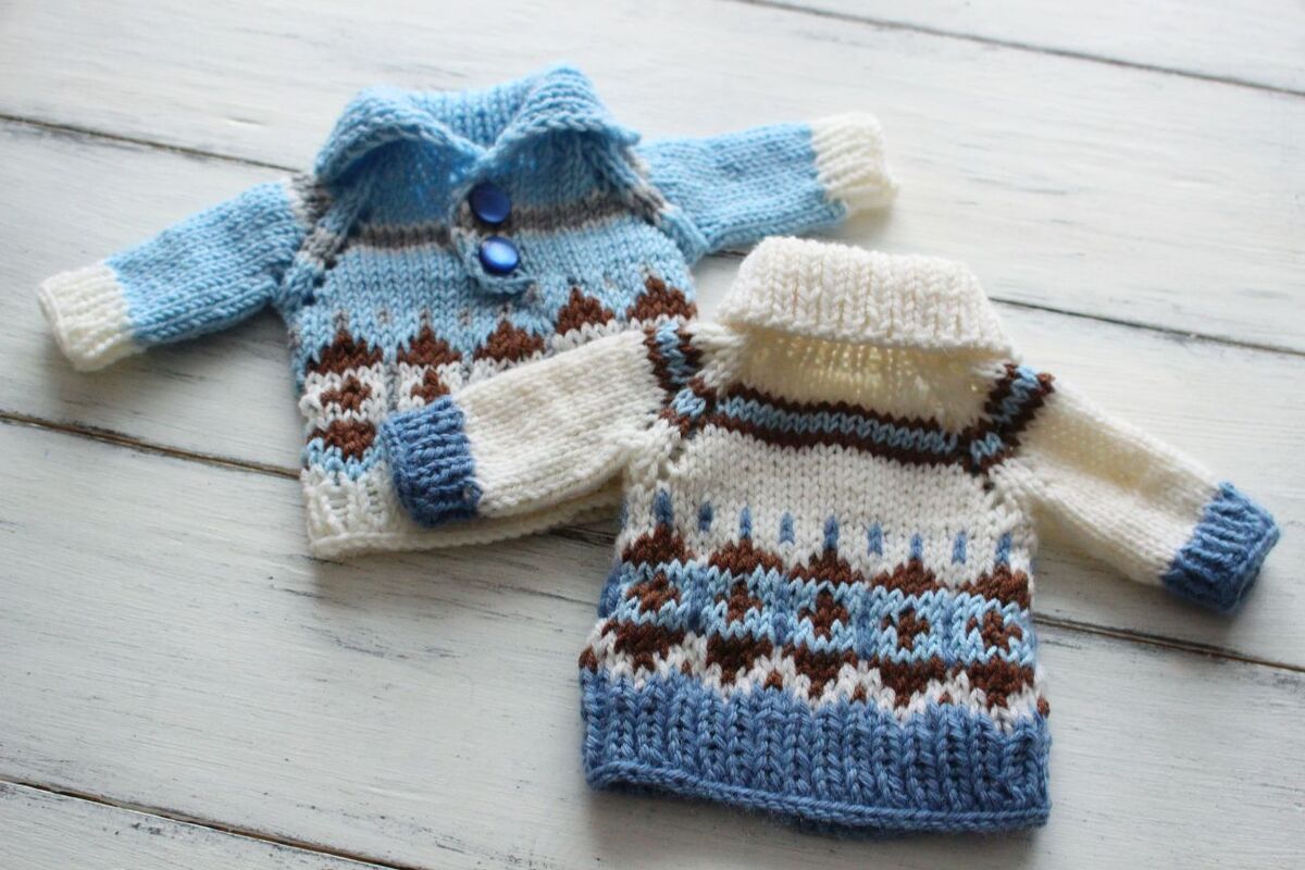 Two miniature knitted sweaters: blue collared with buttons and cream roll-neck with patterned motifs.